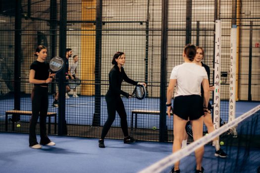 Indoor padel tennis game with multiple players preparing for a match.
